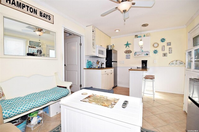 50 Rampasture Rd Unit 6, Hampton Bays, NY 11946 - kitchen featuring a ceiling fan, freestanding refrigerator, white microwave, light tile patterned flooring, and wainscoting