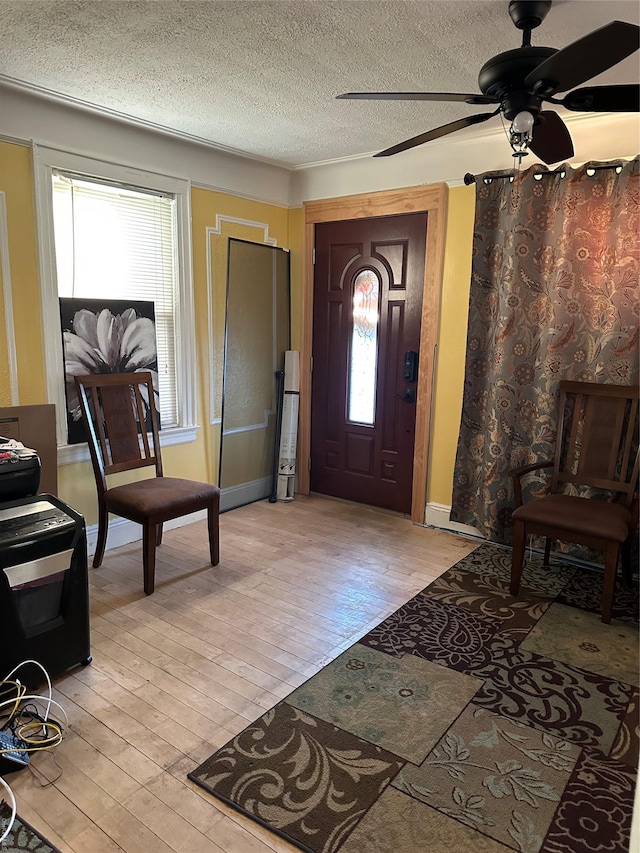 foyer entrance featuring a textured ceiling, light hardwood / wood-style flooring, and ceiling fan