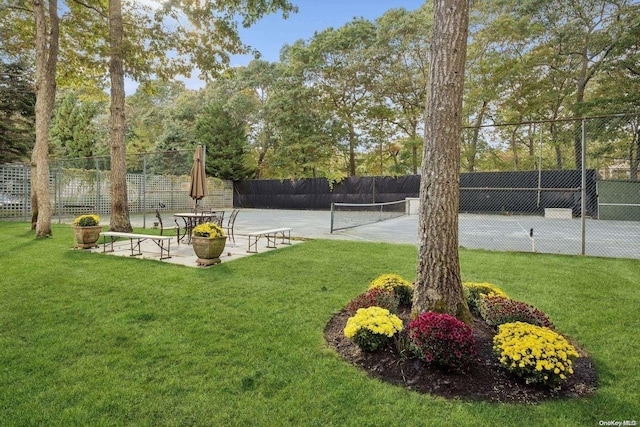 view of home's community with tennis court and a yard