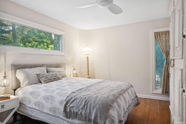 bedroom featuring ceiling fan, dark hardwood / wood-style floors, and multiple windows