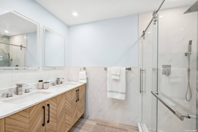 bathroom with hardwood / wood-style floors, vanity, a shower with door, and backsplash