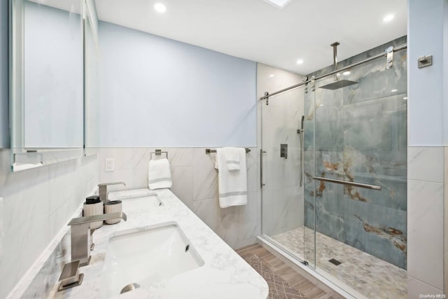 bathroom featuring hardwood / wood-style flooring, vanity, a shower with door, and tile walls