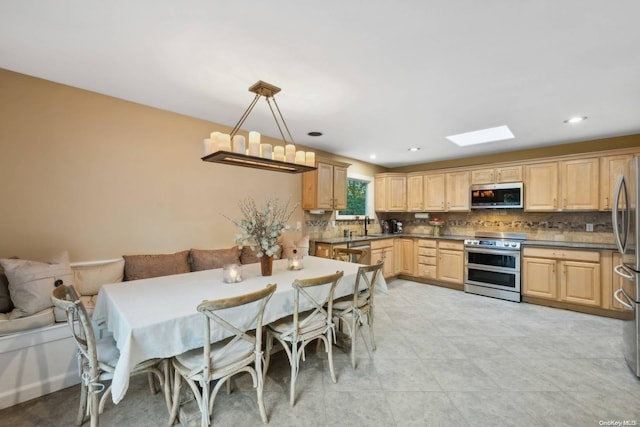 kitchen featuring appliances with stainless steel finishes, tasteful backsplash, sink, light brown cabinets, and decorative light fixtures