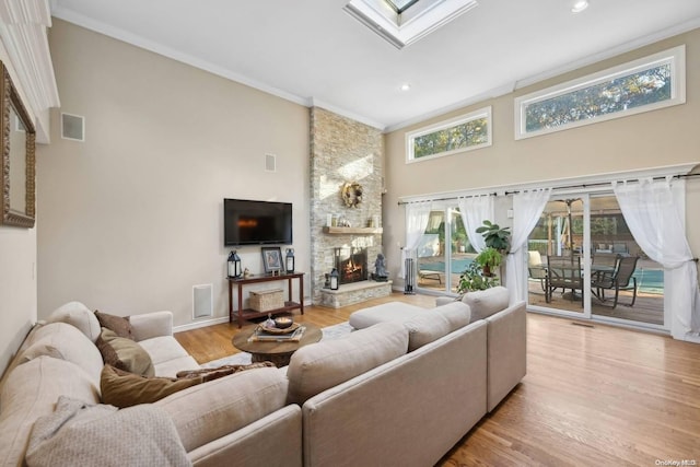 living room featuring a fireplace, a skylight, crown molding, and light hardwood / wood-style flooring