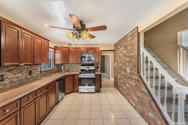 kitchen with light stone countertops, stainless steel appliances, ceiling fan, sink, and light tile patterned floors