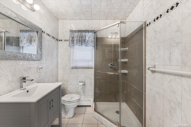 bathroom with tile patterned floors, vanity, tile walls, toilet, and a shower with shower door