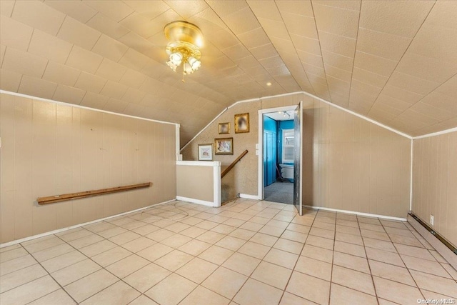 additional living space with tile patterned floors, wood walls, and vaulted ceiling