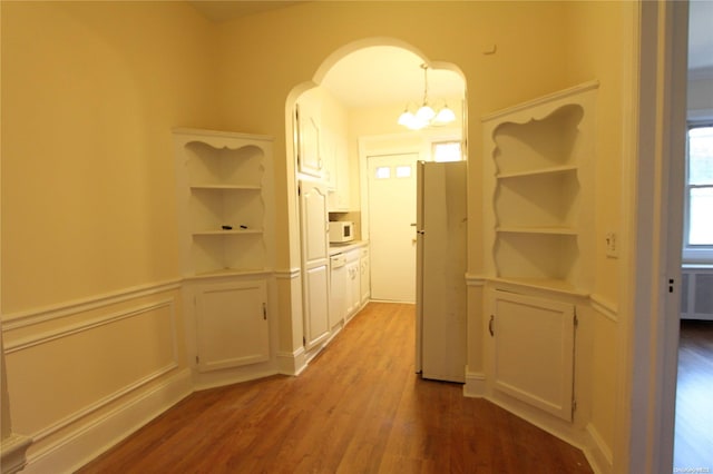 hallway with light hardwood / wood-style floors and an inviting chandelier