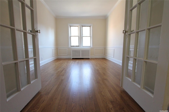 unfurnished room featuring dark hardwood / wood-style floors, radiator heating unit, crown molding, and french doors