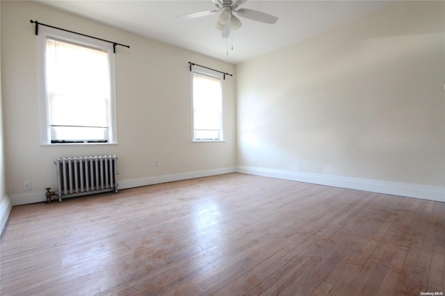 unfurnished room featuring radiator heating unit, light wood-type flooring, and ceiling fan