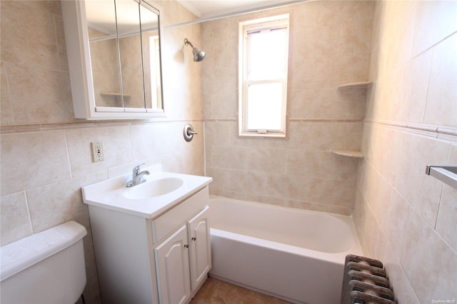 full bathroom with radiator, vanity, tile walls, toilet, and tiled shower / bath