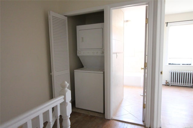 washroom featuring hardwood / wood-style flooring, radiator, and stacked washer and clothes dryer