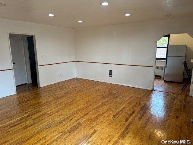 empty room featuring hardwood / wood-style floors and radiator heating unit