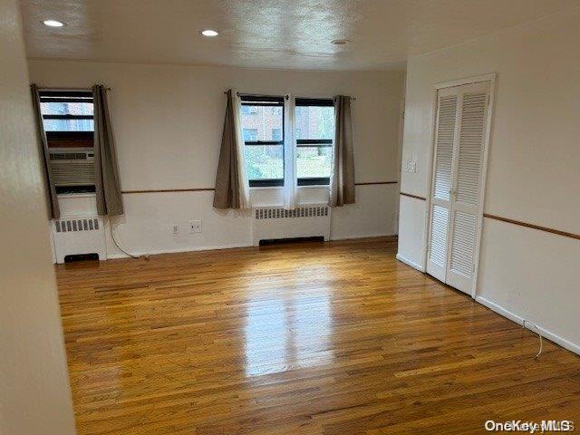 spare room with radiator heating unit, light wood-type flooring, and a textured ceiling