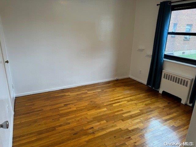 empty room featuring radiator heating unit and light hardwood / wood-style flooring