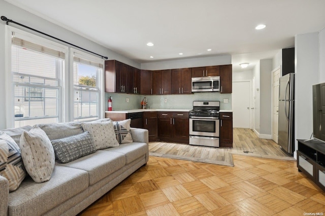 kitchen featuring decorative backsplash, dark brown cabinets, and appliances with stainless steel finishes