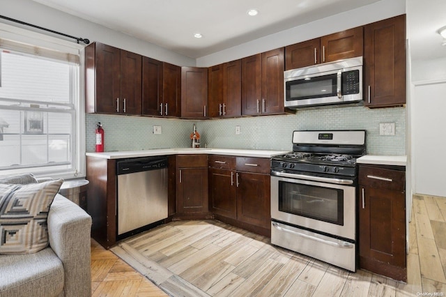 kitchen with backsplash, dark brown cabinetry, light hardwood / wood-style floors, and appliances with stainless steel finishes