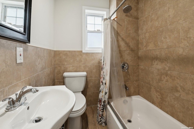 full bathroom featuring shower / bath combo, toilet, sink, and tile walls