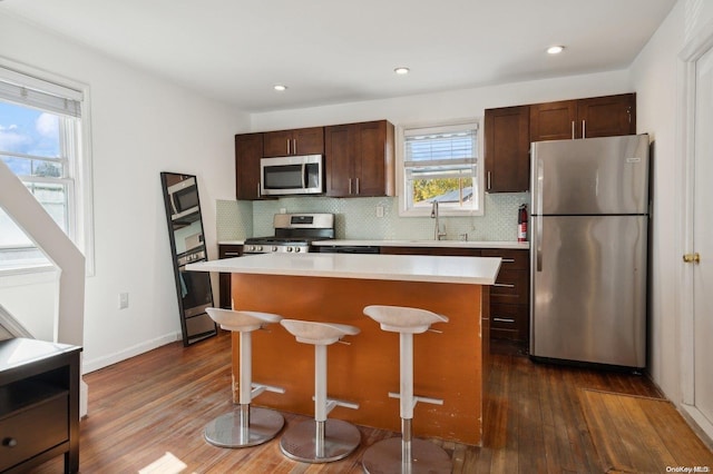 kitchen with appliances with stainless steel finishes, a center island, dark hardwood / wood-style flooring, and sink