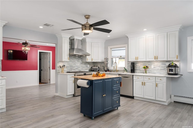 kitchen featuring white cabinetry, wall chimney exhaust hood, stainless steel appliances, wood counters, and blue cabinets