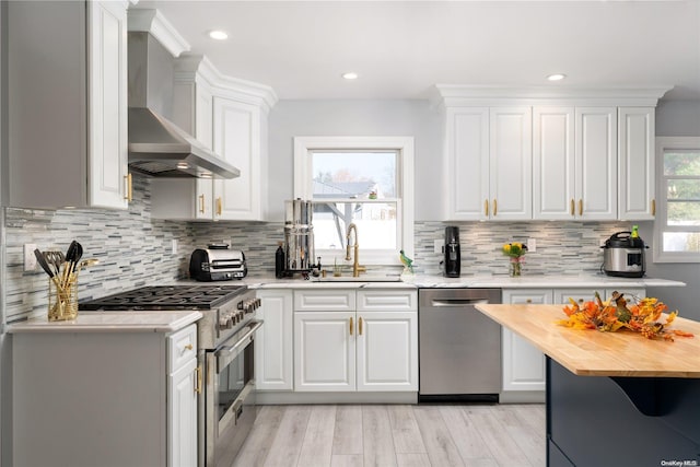 kitchen with wooden counters, white cabinets, stainless steel appliances, and sink