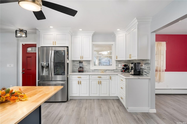 kitchen with decorative backsplash, white cabinetry, stainless steel fridge with ice dispenser, and baseboard heating