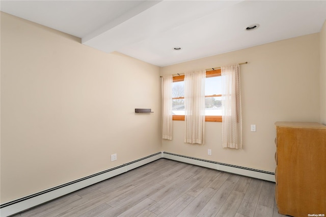 unfurnished room featuring a baseboard radiator and light hardwood / wood-style flooring