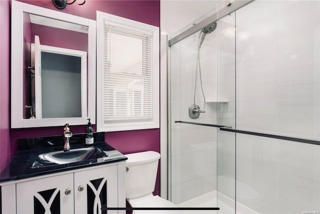 bathroom featuring vanity, toilet, and a shower with shower door