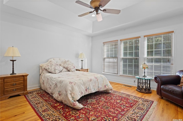 bedroom featuring hardwood / wood-style floors, ceiling fan, and multiple windows