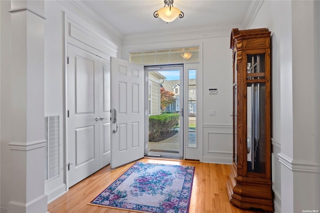 foyer entrance with light hardwood / wood-style floors and crown molding