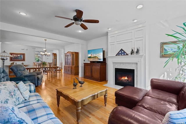 living room featuring ceiling fan with notable chandelier and light hardwood / wood-style flooring