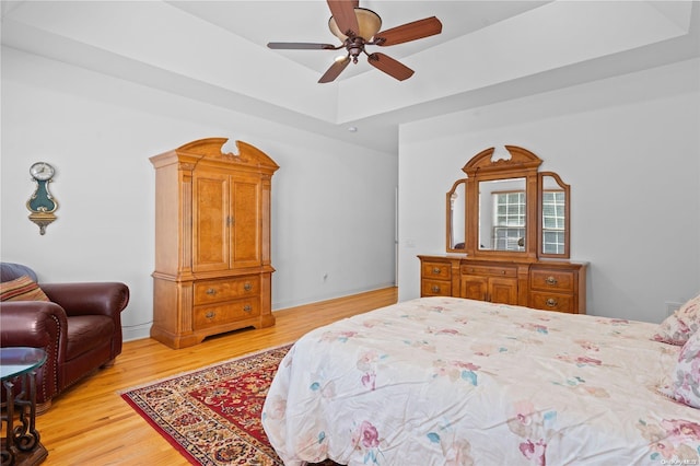 bedroom featuring a tray ceiling, ceiling fan, and light hardwood / wood-style flooring