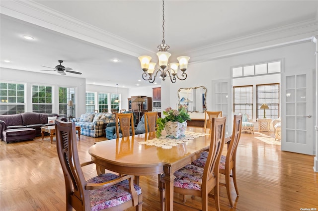 dining area with crown molding, ceiling fan with notable chandelier, and light wood-type flooring