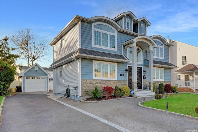 view of front of home featuring a garage, an outbuilding, and a front lawn