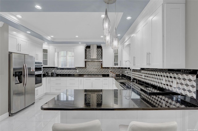 kitchen with wall chimney exhaust hood, stainless steel appliances, kitchen peninsula, pendant lighting, and a kitchen bar