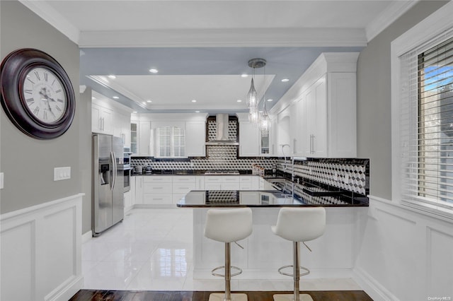 kitchen with kitchen peninsula, pendant lighting, wall chimney range hood, and appliances with stainless steel finishes