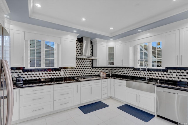 kitchen featuring wall chimney range hood, sink, decorative backsplash, ornamental molding, and stainless steel appliances