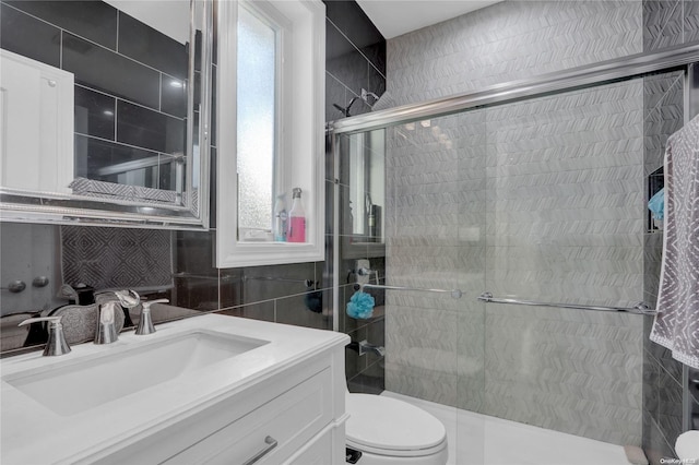 bathroom featuring vanity, toilet, walk in shower, and tile walls