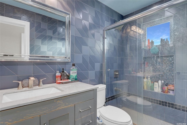 bathroom with decorative backsplash, vanity, a shower with door, tile walls, and toilet