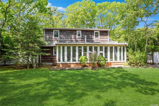 rear view of property featuring a sunroom and a yard