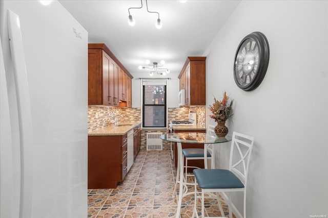 83-05 98th St Unit 4G, Woodhaven, NY 11421 - kitchen with backsplash, brown cabinets, a breakfast bar area, light stone countertops, and a chandelier