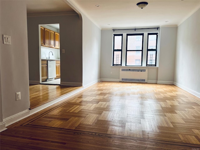 80-09 35th Ave Unit C16, Jackson Heights, NY 11372 - empty room featuring radiator, crown molding, baseboards, arched walkways, and a sink