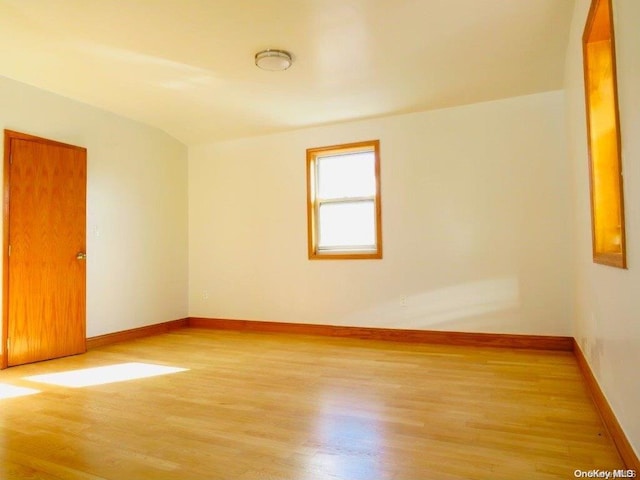 empty room with light wood-type flooring and vaulted ceiling