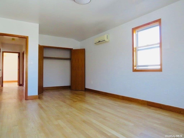 unfurnished bedroom featuring light hardwood / wood-style floors, an AC wall unit, and a closet