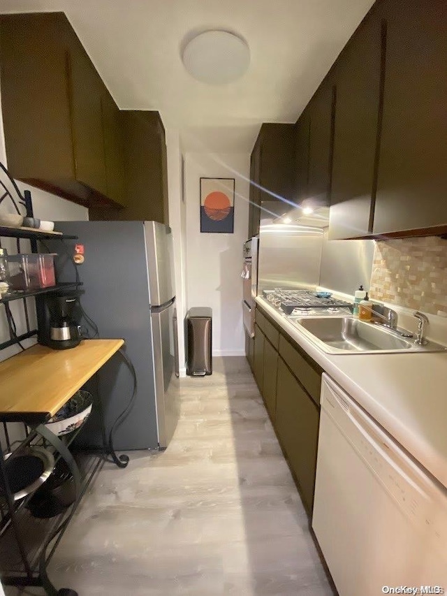 kitchen with dishwasher, sink, light wood-type flooring, tasteful backsplash, and stainless steel refrigerator