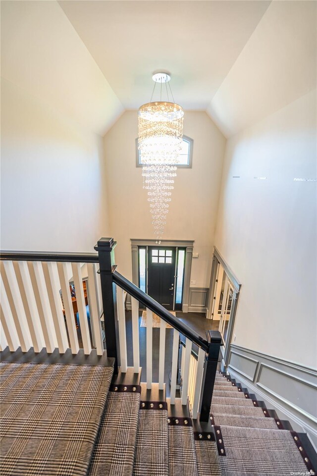 stairway with carpet, lofted ceiling, and an inviting chandelier