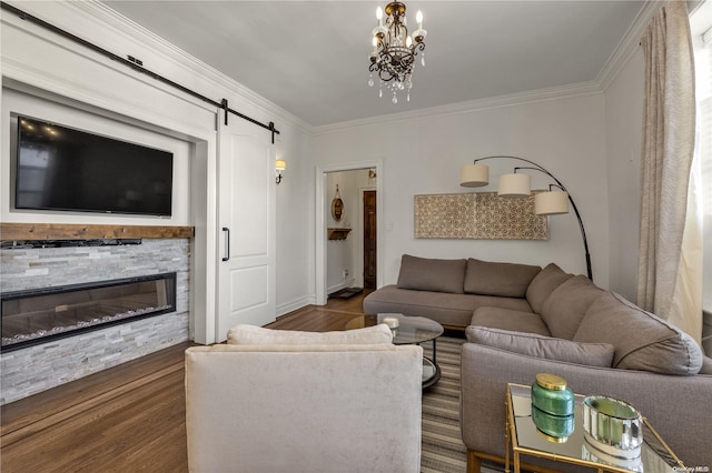 living room featuring a barn door, dark hardwood / wood-style flooring, a notable chandelier, a fireplace, and ornamental molding