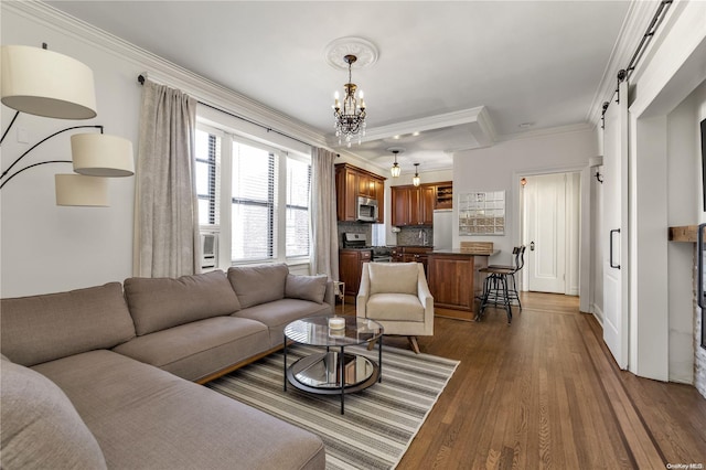 living room with a chandelier, a barn door, dark hardwood / wood-style floors, and ornamental molding