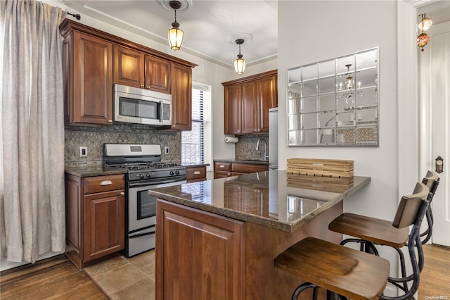 kitchen featuring stainless steel appliances, tasteful backsplash, light hardwood / wood-style flooring, pendant lighting, and a breakfast bar