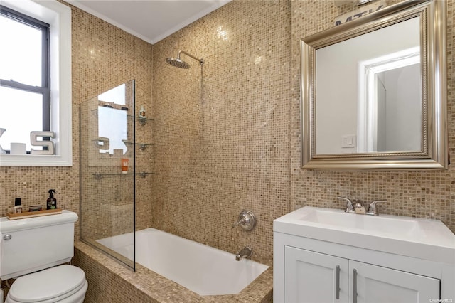 full bathroom featuring tiled shower / bath, toilet, vanity, tile walls, and ornamental molding